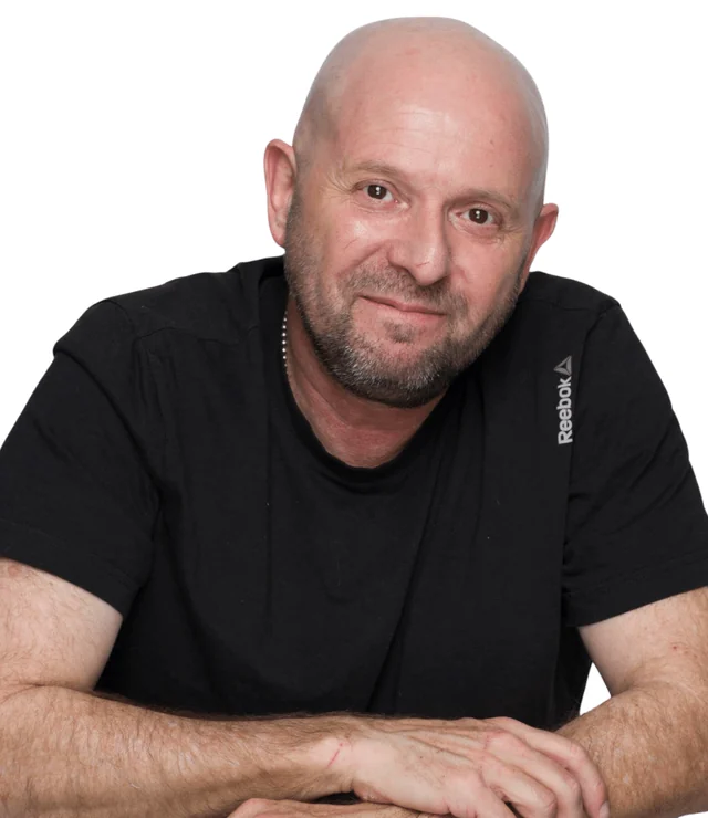 טל פרידמן, גזור עם מסגרת מדבקה לבנה, מחייך כאילו הביא אשכוליות.